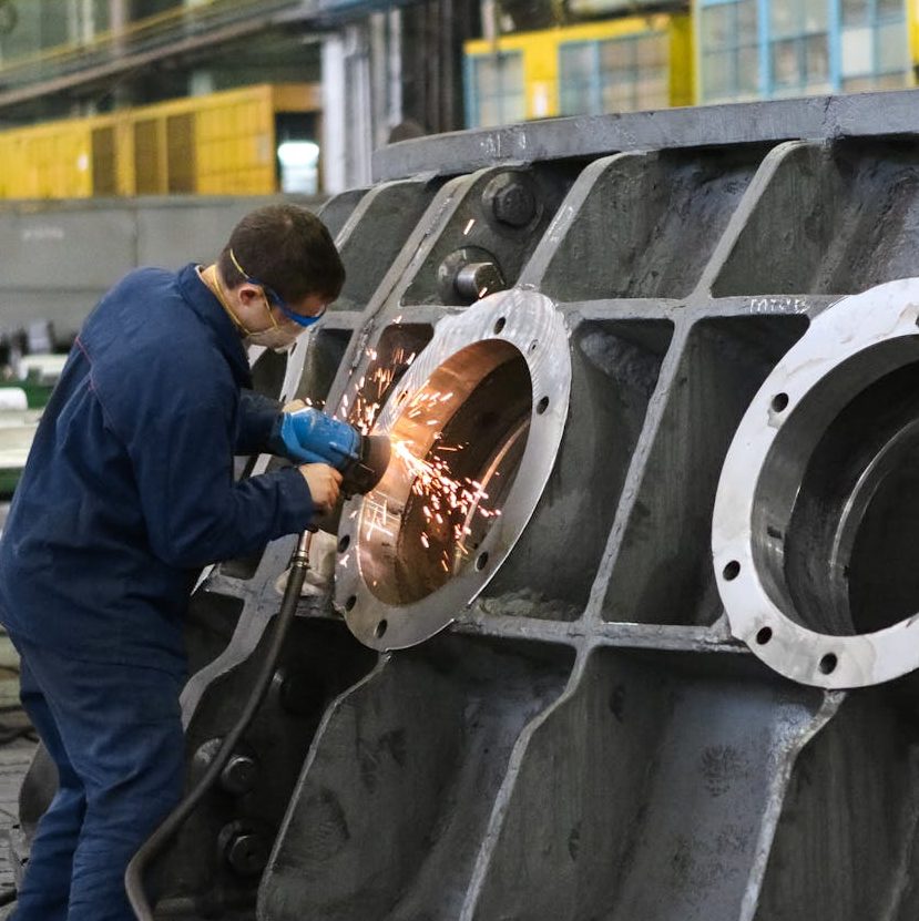 Industrial mechanic uses metal grinder to polish a large object