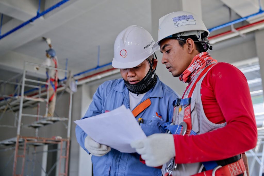 Construction Managers in hard hats look at worksite documents