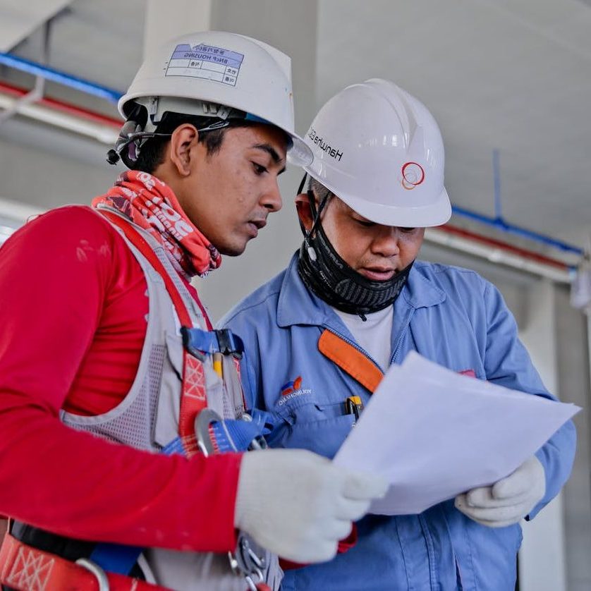 Construction Managers in hard hats look at worksite documents