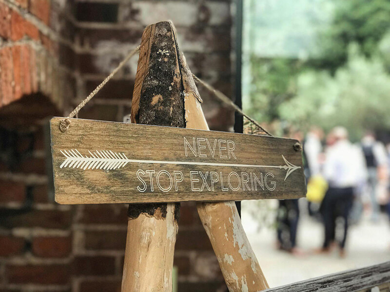 A rustic sign made of rough cut pine that says never stop exploring