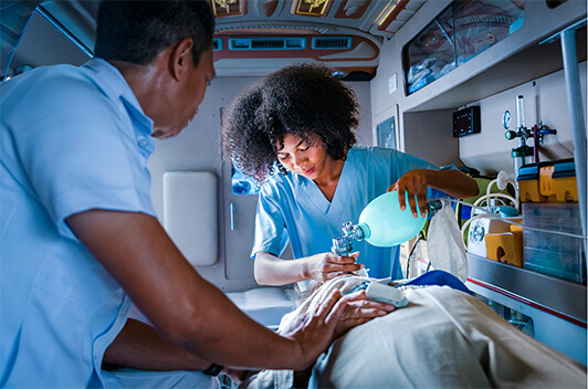 Paramedics in ambulance use a breathing pump