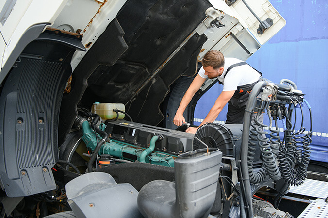 Bus and truck diesel engine mechanic specialist works under hood of semi truck