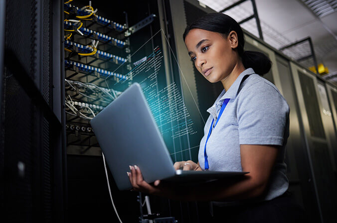 Young, female Computer Information Science CIS major or analyst holding laptop near server rack