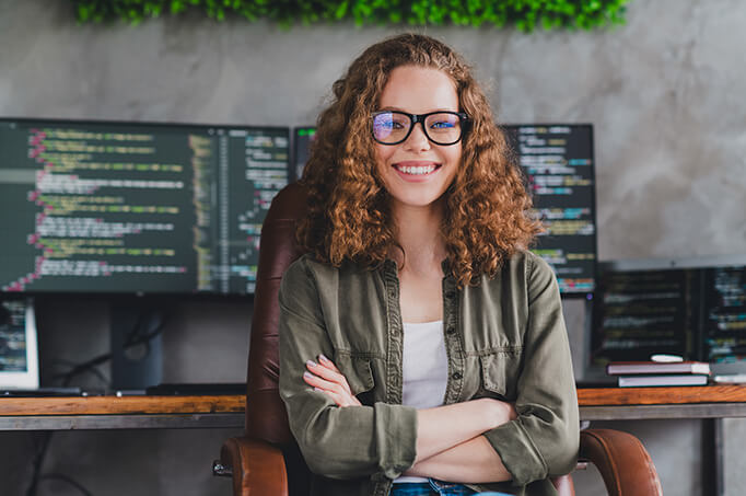 Young female software developer or coder smiles in front of computer