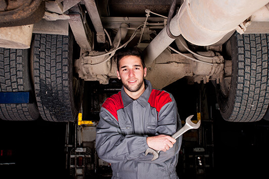 Diesel truck mechanic works under truck